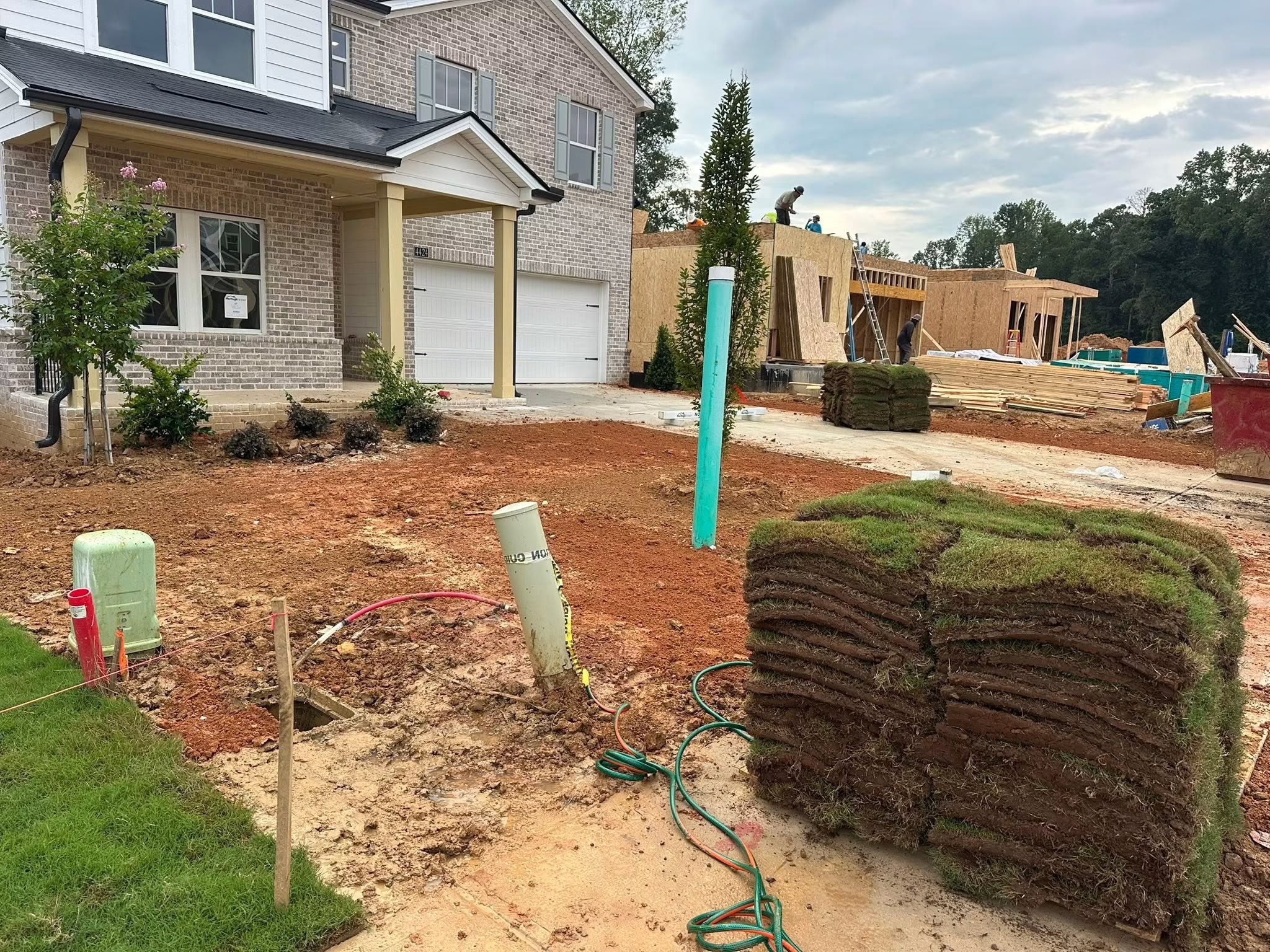 Before: exposed clay soil with sod pallets ready for installation