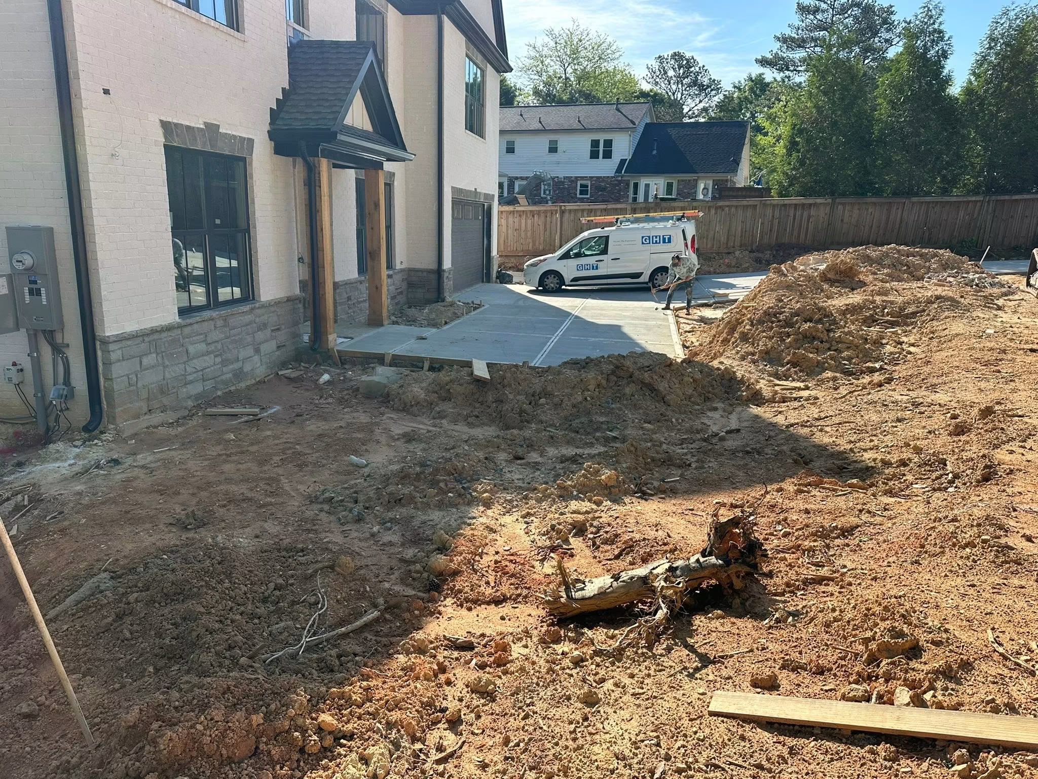 Before: rough dirt lot with excavation mounds and exposed tree roots